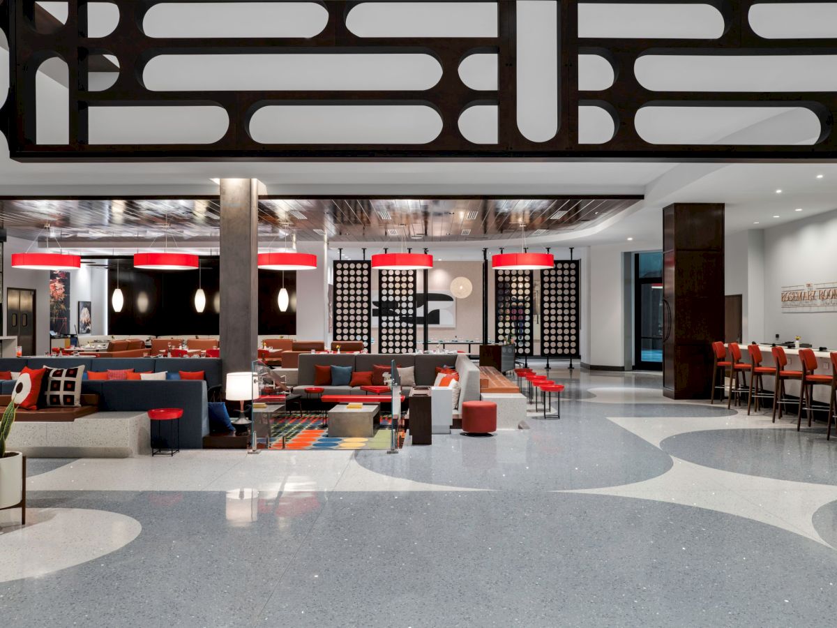 A modern, stylish restaurant interior with artistic decor, red light fixtures, bar seating, and a vibrant, open atmosphere.